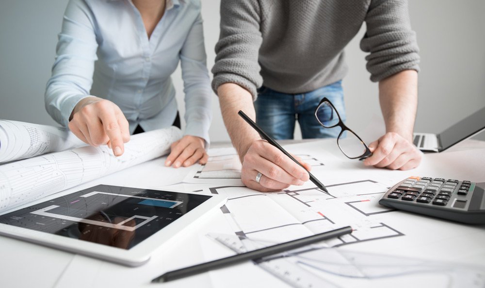 two people leaning over the plan of the kitchen